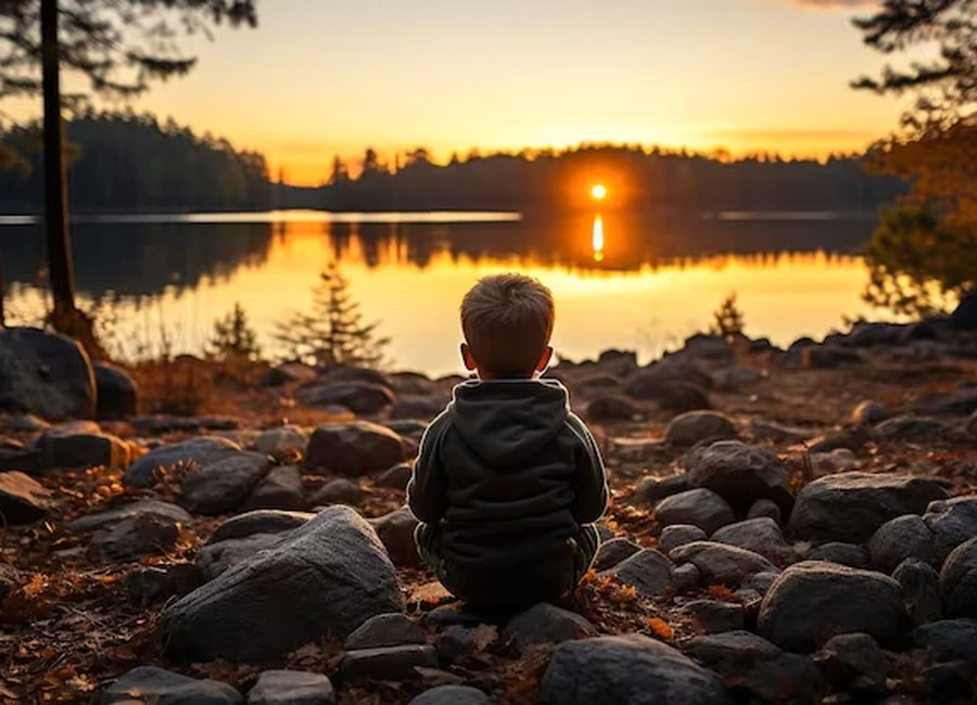 Niño frente al lago al atardecer